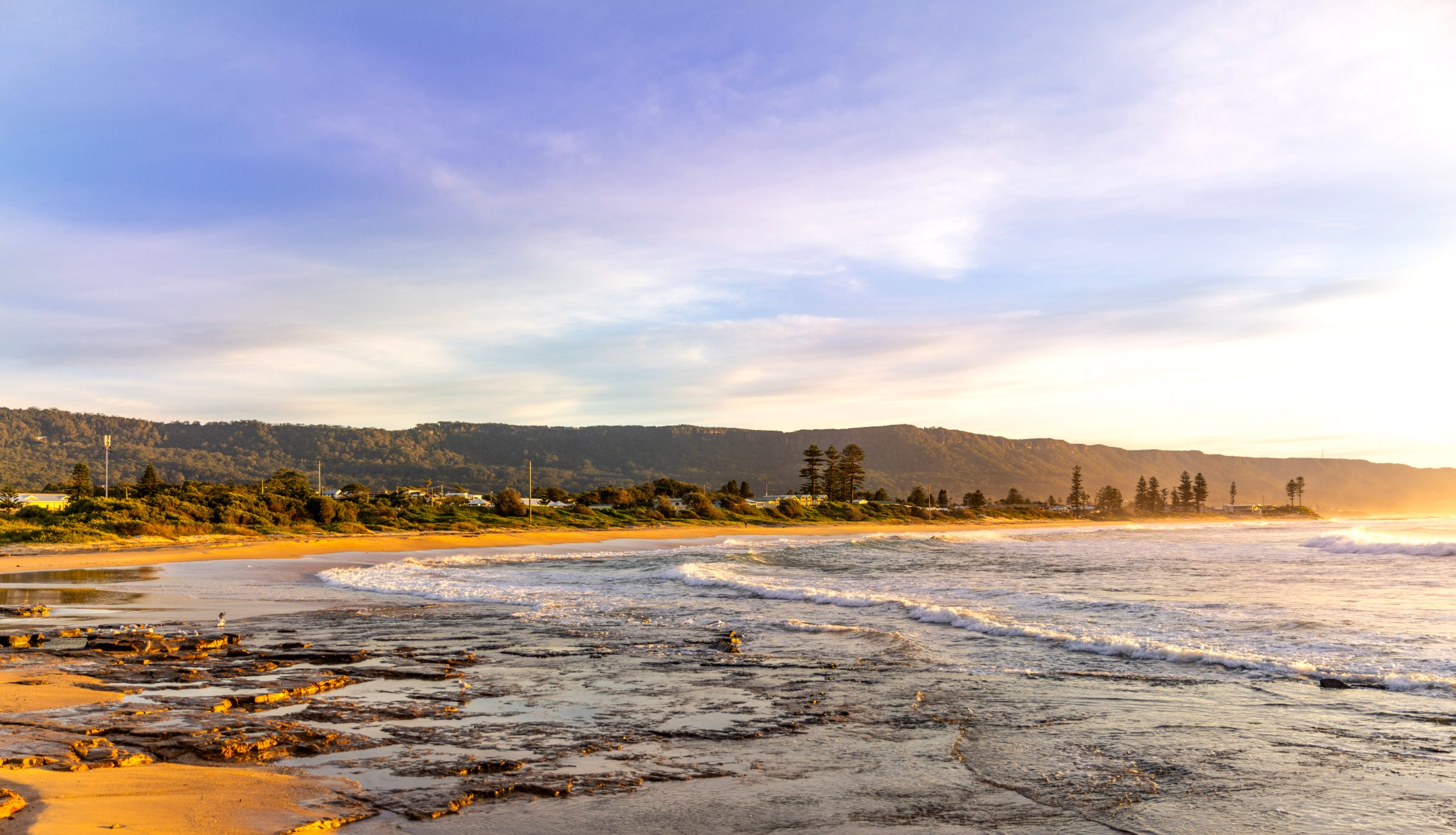South Coast beach at golden hour, escarpment behind the town